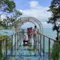 Pengunjung berjalan di atas jembatan kaca sambil menikmati keindahan alam Mentari Ocean View. (Foto: Trinoto - Lensa Pacitan)